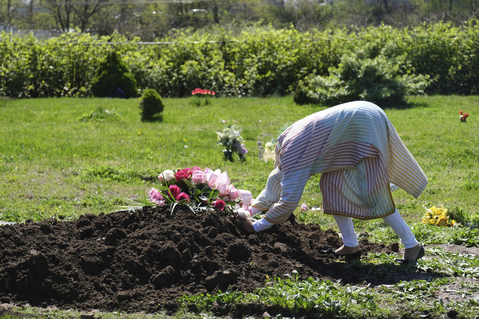 Erika Bermudez se reclina sobre la tumba de su madre Eudiana Smith, fallecida de COVID-19, que fue sepultada el sábado 2 de mayo de 2020 en el cementerio Bayview en Jersey City, Nueva Jersey. Se permitió a Bermudez acercarse al lugar hasta después de que Smith fue totalmente inhumada. Amigos y parientes tuvieron que permanecer en sus vehículos. (AP Foto/Seth Wenig)