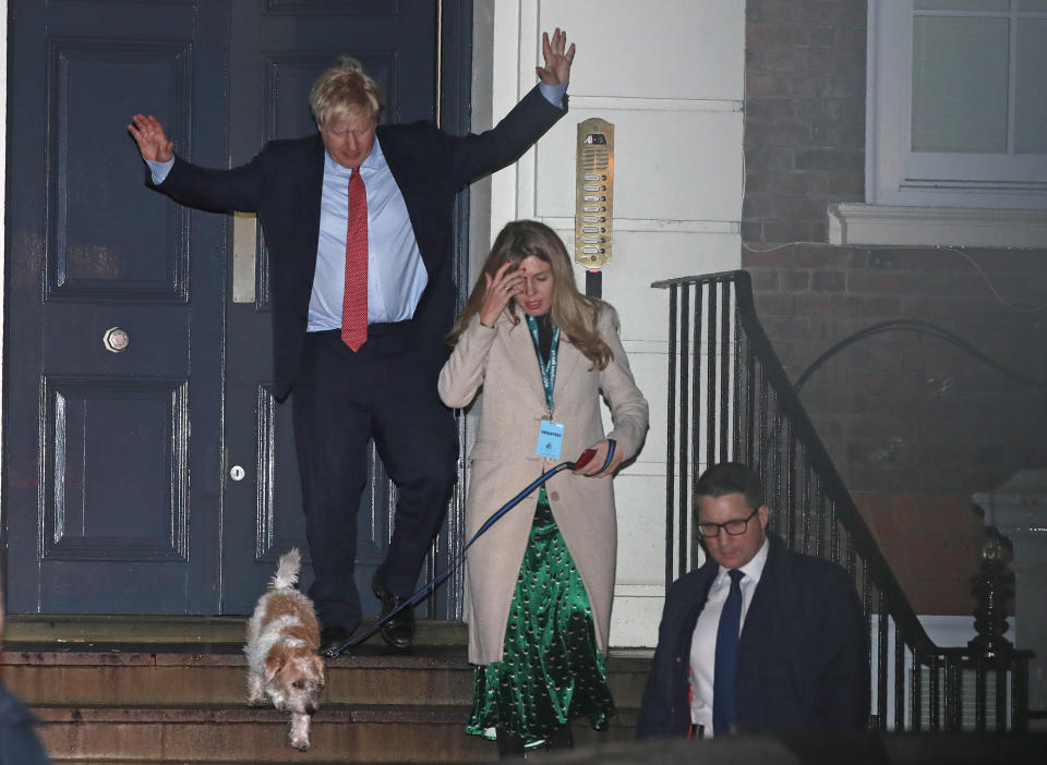 Britain's Prime Minister and Conservative Party leader Boris Johnson leaves Conservative Party headquarters with his partner Carrie Symonds and their dog Dilyn, in London, Friday, Dec. 13, 2019. Prime Minister Boris Johnson's Conservative Party appeared on course Friday to win a solid majority of seats in Britain's Parliament— a decisive outcome to a Brexit-dominated election that should allow Johnson to fulfill his plan to take the U.K. out of the European Union next month. (AP Photo/Thanassis Stavrakis)