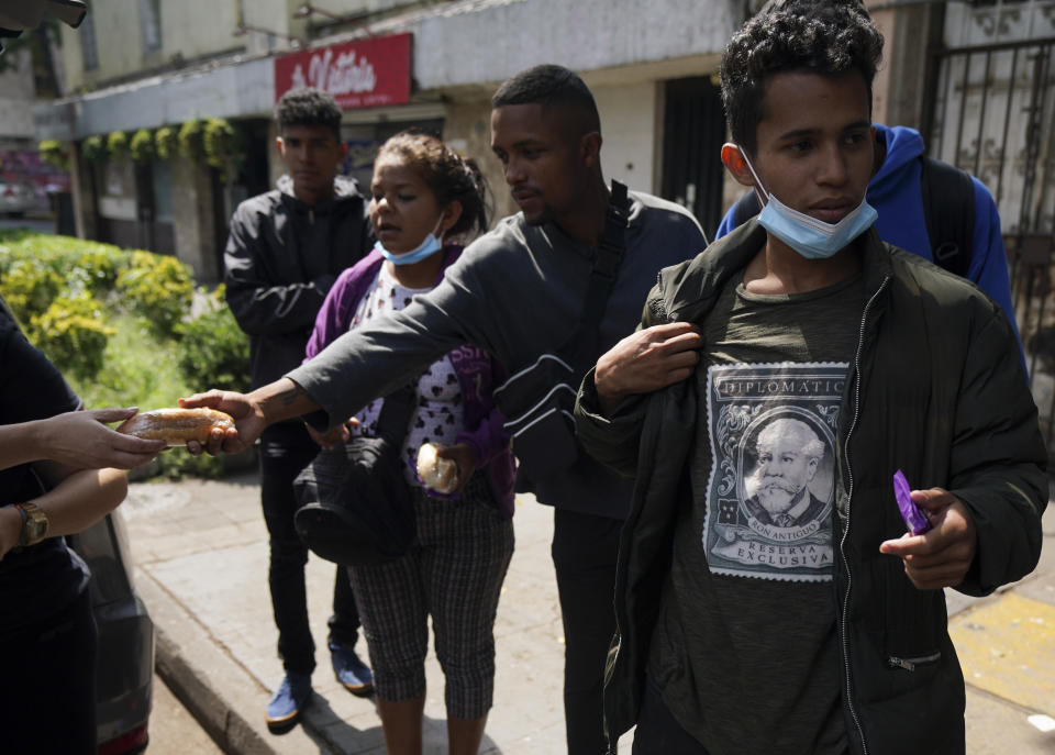 Volunteers deliver food to Venezuelan migrants that seek assistance outside the Mexican Commission for Refugee Aid in Mexico City, Thursday, Oct. 20, 2022. These Venezuelan migrants were returned to Mexico by U.S. immigration authorities after crossing the border last week. (AP Photo/Fernando Llano)