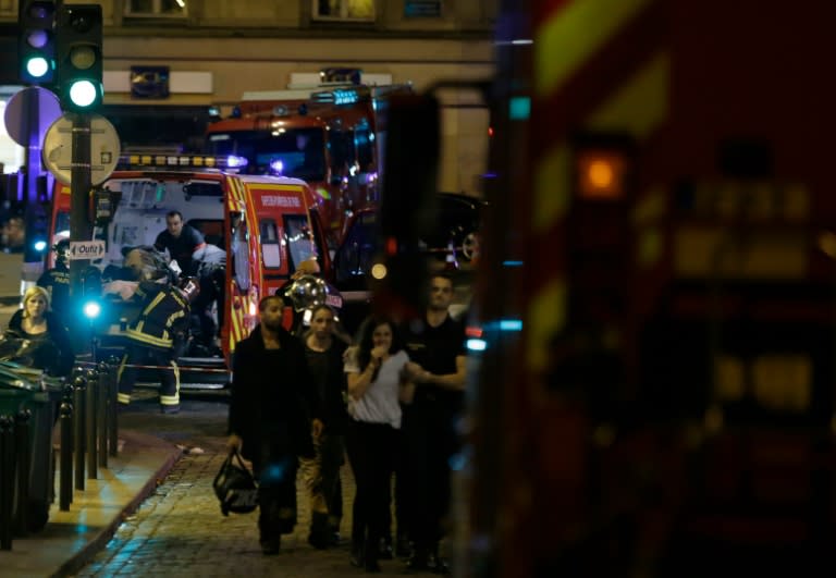 A woman is evacuated as rescuers ferry an injured person into an ambulance in the 10th arrondissement of the French capital Paris, on November 13, 2015