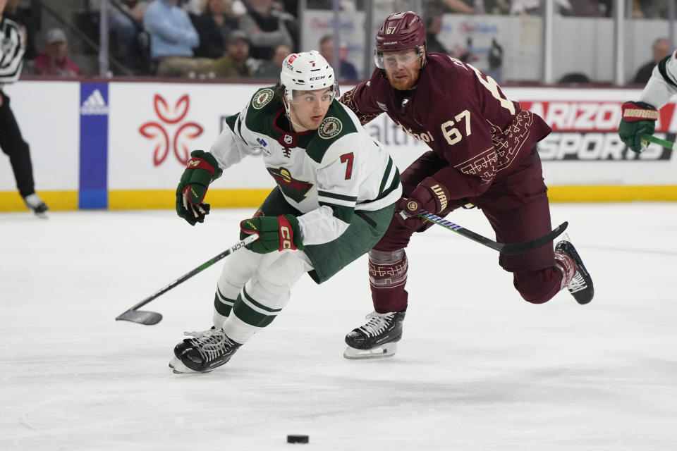 Minnesota Wild defenseman Brock Faber (7) shields Arizona Coyotes left wing Lawson Crouse from the puck in the third period during an NHL hockey game, Thursday, March 7, 2024, in Tempe, Ariz. Minnesota won 5-2. (AP Photo/Rick Scuteri)