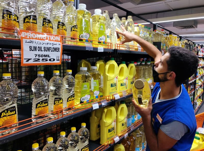 A worker arranges bottles of oil inside inside a supermarket in Beirut