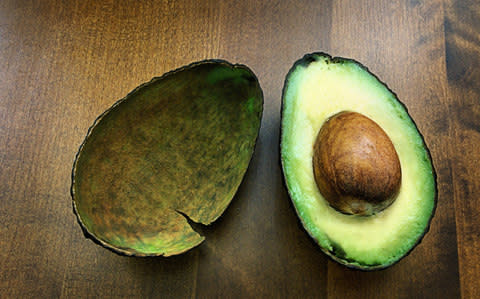 Fresh avocado cut in half on wooden table top - Credit: Michelle McMahon/Moment RF