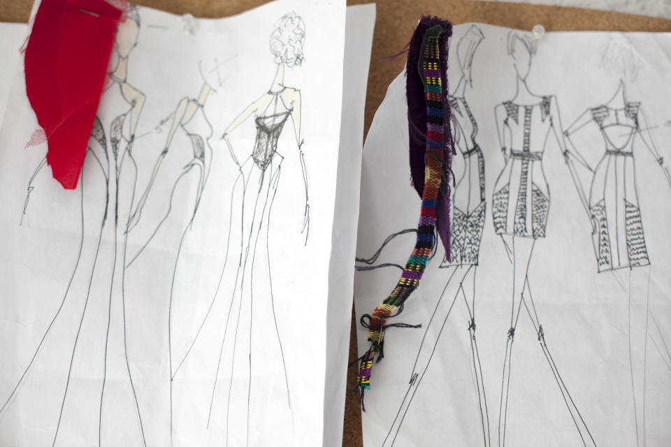 In this Aug. 21, 2013 photo, sketches with pieces of textiles attached of designs by Eduardo Figuero are tacked to a board, in his studio in Guatemala City. Embroidered Mayan textiles known as huipiles are undergoing a revival in some of the country’s finest boutiques as they become a haute couture fixture. Young Guatemalan designers are using them for everything from evening gowns and purses to handmade shoes sold as far away as Dubai. (AP Photo/Luis Soto)