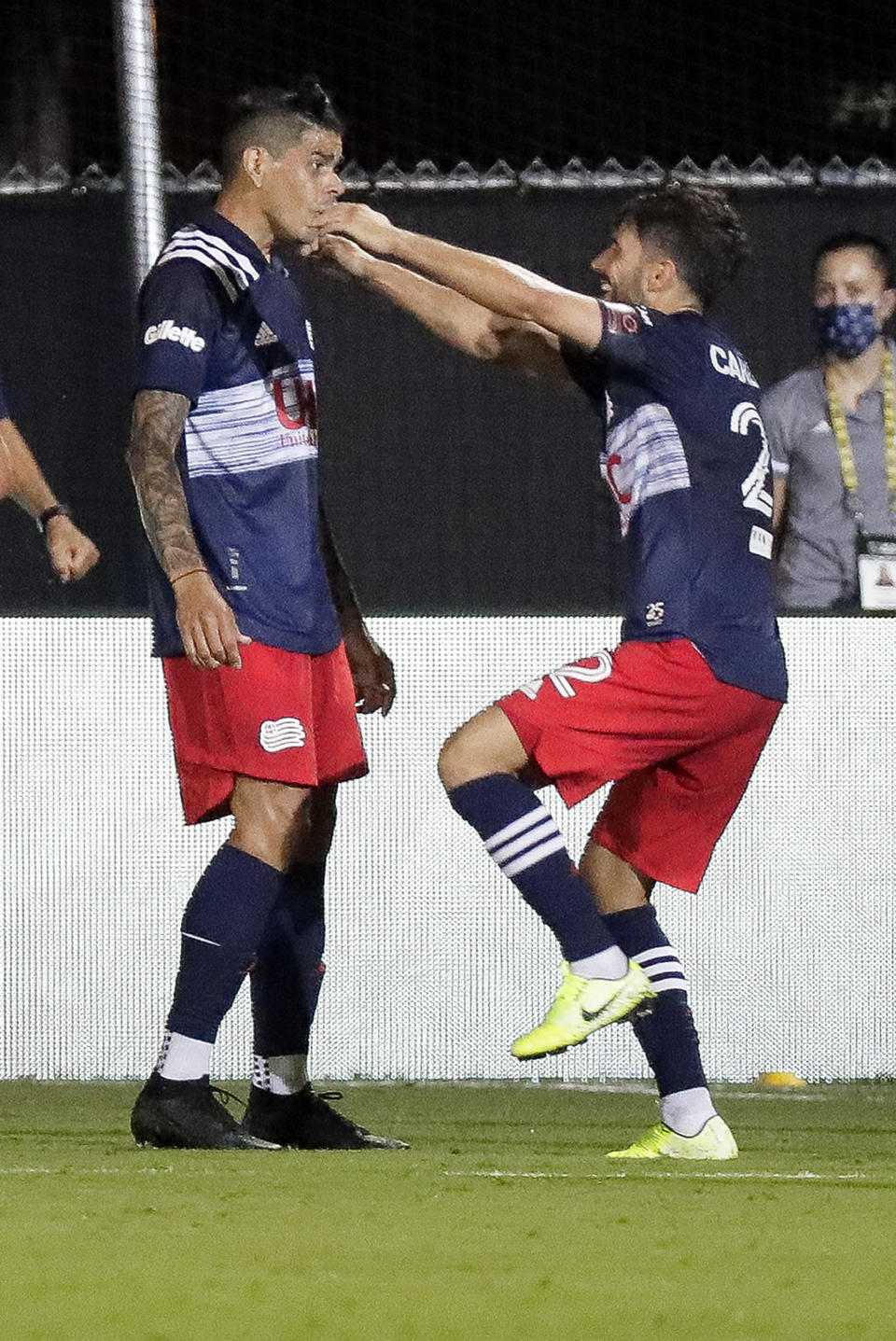 Carles Gil, del Revolution de Nueva Inglaterra, salta a los brazos del argentino Gustavo Bou, quien anotó el tanto del triunfo sobre el Impact de Montreal, el jueves 9 de julio de 2020, en Kissimmee, Florida (AP Foto/John Raoux)