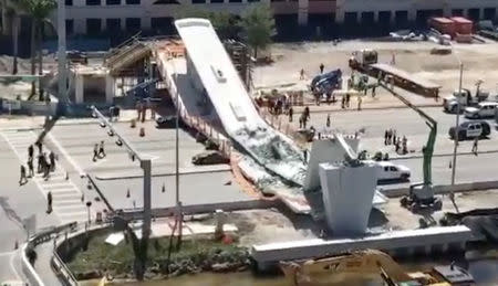 Emergency crews work at the scene of a collapsed pedestrian bridge at Florida International University in Miami, Florida March 15, 2018 in this still image obtained from social media video. Instagram/ @BRANDONX868 via REUTERS