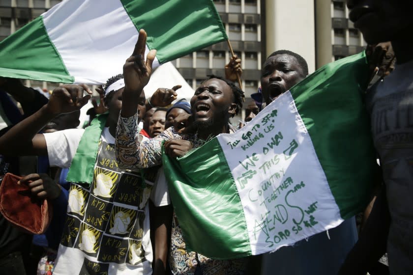 People hold banners as they demonstrate on the street to protest against police brutality, in Lagos, Nigeria, Tuesday Oct. 20, 2020. After 13 days of protests against police brutality, authorities have imposed a 24-hour curfew in Lagos, Nigeria's largest city as moves are made to stop growing violence. (AP Photo/Sunday Alamba)