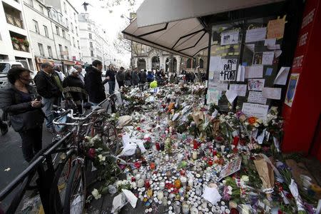 People look at flowers, candles and messages in tribute to victims in front of the La Belle Equipe cafe, one of the sites of the deadly attacks in Paris, France, November 17, 2015. REUTERS/Jacky Naegelen