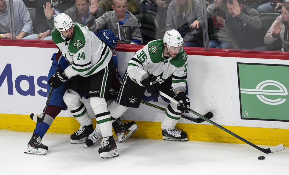Dallas Stars center Matt Duchene, right, collects the puck as left wing Jamie Benn, front left, pins Colorado Avalanche left wing Artturi Lehkonen to the boards during the third period of Game 3 of an NHL hockey Stanley Cup playoff series Saturday, May 11, 2024, in Denver. (AP Photo/David Zalubowski)