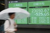 A woman walks by an electronic stock board of a securities firm in Tokyo, Wednesday, Jan. 8, 2020. Oil prices rose and Asian stock markets fell Wednesday after Iran fired missiles at U.S. bases in Iraq in retaliation for the killing of an Iranian general. Tokyo's stock market benchmark fell nearly 2%. (AP Photo/Koji Sasahara)