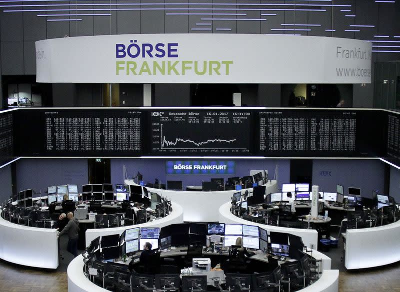 Traders work at their desks in front of the German share price index, DAX board, at the stock exchange in Frankfurt, Germany, January 16, 2017. REUTERS/Staff/Remote