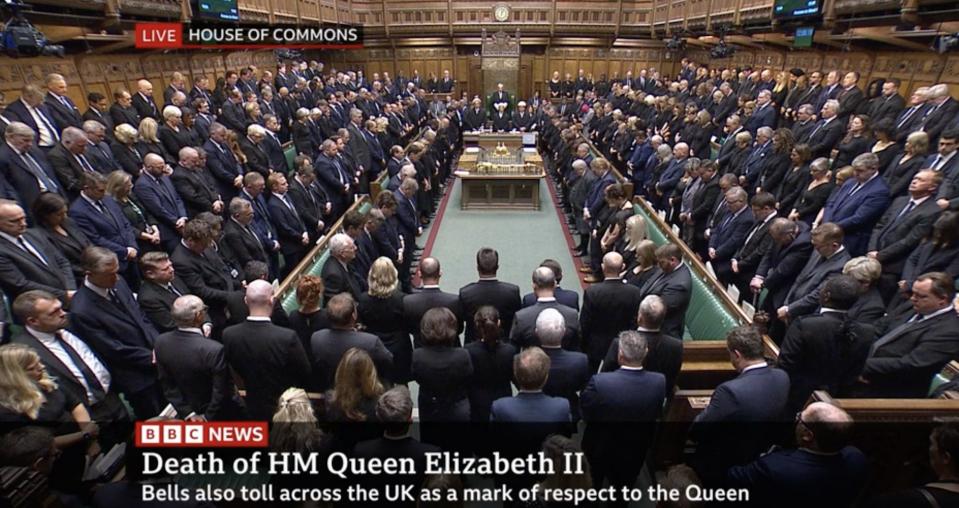 Members of the UK House of Commons standing and wearing dark clothing