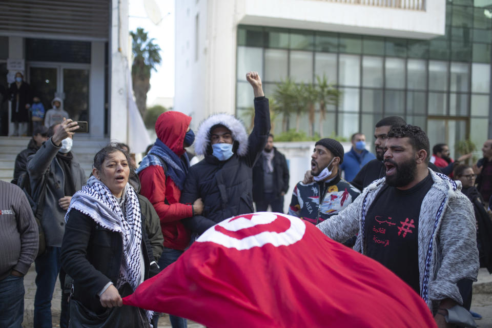 A small group of people take part in a protest on the tenth anniversary of the uprising that toppled longtime autocrat Ben Ali , during to a national lockdown after a surge in COVID-19 cases, in Tunis, Thursday, Jan. 14, 2021. Tunisia is commemorating the 10th anniversary since the flight into exile of its iron-fisted leader, Zine El Abidine Ben Ali, pushed from power in a popular revolt that foreshadowed the so-called Arab Spring. But there will be no festive celebrations Thursday marking the revolution in this North African nation, ordered into lockdown to contain the coronavirus. (AP Photo/Mosa'ab Elshamy)