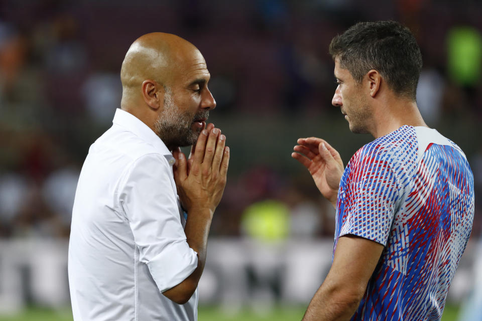 Manchester City's head coach Pep Guardiola, left, gestures as he speaks with Barcelona's Robert Lewandowski end of a charity friendly soccer match between Barcelona and Manchester City at the Camp Nou stadium in Barcelona, Spain, Wednesday, Aug. 24, 2022. (AP Photo/Joan Monfort)