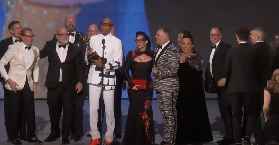 rupaul and the show's producers accepting an award on stage