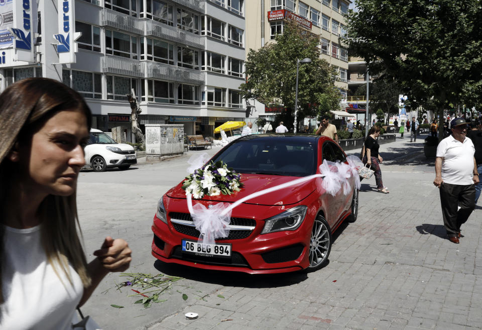 People walk next to a sports car for sale in Ankara, Turkey, Friday, Aug. 17, 2018. Turkey and the United States exchanged new threats of sanctions Friday, keeping alive a diplomatic and financial crisis.(AP Photo/Burhan Ozbilici)