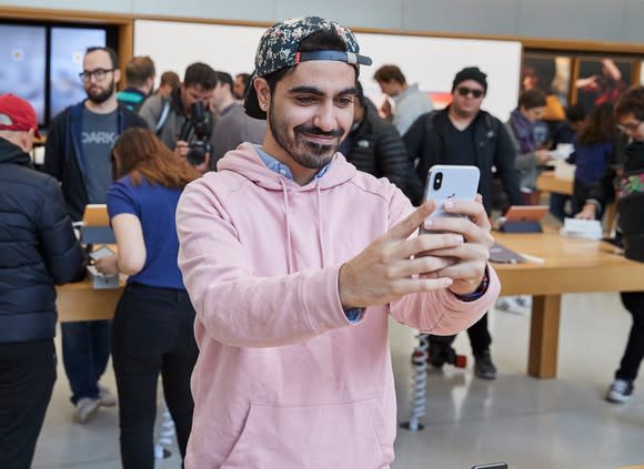 A person holding an iPhone X inside of an Apple store.