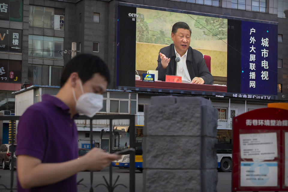 A man wearing a face mask to protect against the new coronavirus walks past a large video screen showing Chinese President Xi Jinping speaking in Beijing, Tuesday, June 30, 2020. China approved a contentious national security law that will allow authorities to crack down on subversive and secessionist activity in Hong Kong, a move many see as Beijing's boldest yet to erase the legal firewall between the semi-autonomous territory and the mainland's authoritarian Communist Party system. (AP Photo/Mark Schiefelbein)