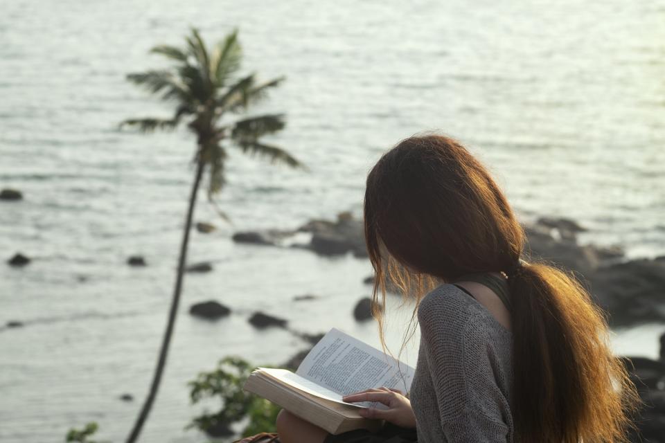 Woman sitting on the rock and reading book