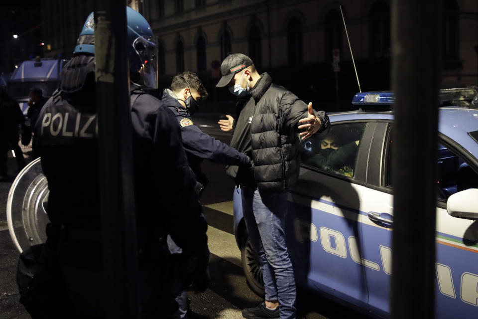 Police detain a man following a protest against the government restriction measures to curb the spread of COVID-19, in Milan Italy, Monday, Oct. 26, 2020. Protesters turned out by the hundreds in Italian several cities and towns on Monday to vent anger, sometimes violently, over the latest anti-COVID-19 rules, which force restaurants and cafes to close early, shutter cinema, gyms and other leisure venues. In the northern city of Turin, demonstrators broke off from a peaceful protest and hurled smoke bombs and bottles at police in the city square where the Piedmont regional government is headquartered. (AP Photo/Luca Bruno)