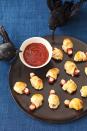 <p>Think pigs in a blanket, with a twist! Guests will love eating these baked cocktail franks wrapped in pie crust strips, with a sliced almond toenail inserted into one end of the digit. Serve with blood-red ketchup for dipping.<br></p><p><strong><a rel="nofollow noopener" href="https://www.womansday.com/food-recipes/food-drinks/recipes/a11471/severed-toes-in-bandages-recipe-122709/" target="_blank" data-ylk="slk:Get the recipe.;elm:context_link;itc:0;sec:content-canvas" class="link ">Get the recipe.</a></strong></p>