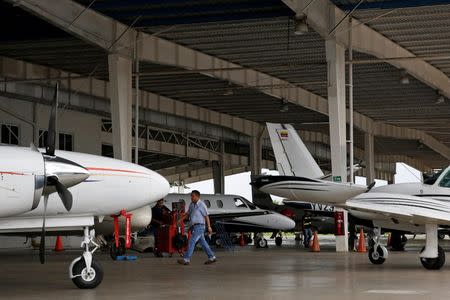 A worker walks next to private planes in one of the hangars at Charallave airport outside Caracas September 15, 2014. REUTERS/Carlos Garcia Rawlins