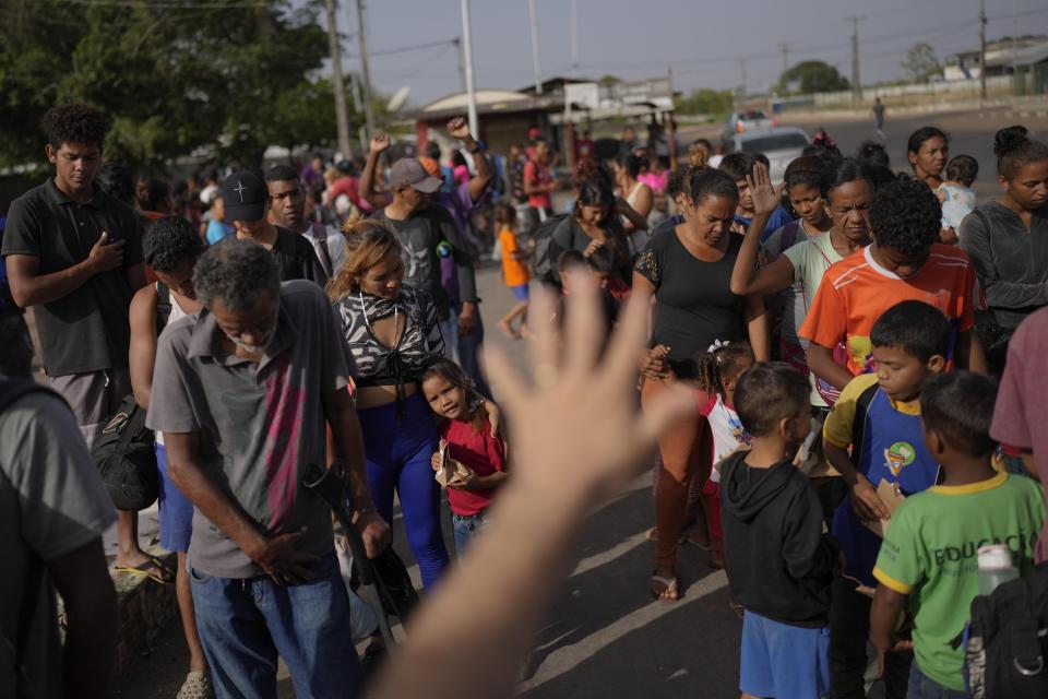 Grace of God International church pastor blesses Venezuelan migrants as they wait for breakfast provided by the church in Boa Vista, Roraima state, Brazil, Friday, April 7, 2023. (AP Photo/Matias Delacroix)