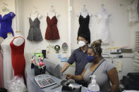 Christina Anderson, right, shops for fashion in bulk for the store RichNPure with the help of a store owner Wednesday, May 27, 2020, in Los Angeles. California moved to further relax its coronavirus restrictions and help the battered economy. Retail stores, including those at shopping malls, can open at 50% capacity. (AP Photo/Marcio Jose Sanchez)