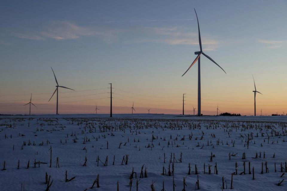 A wind farm shares space with corn fields the day before the Iowa caucuses, where agriculture and clean energy are key issues, in Latimer, Iowa.