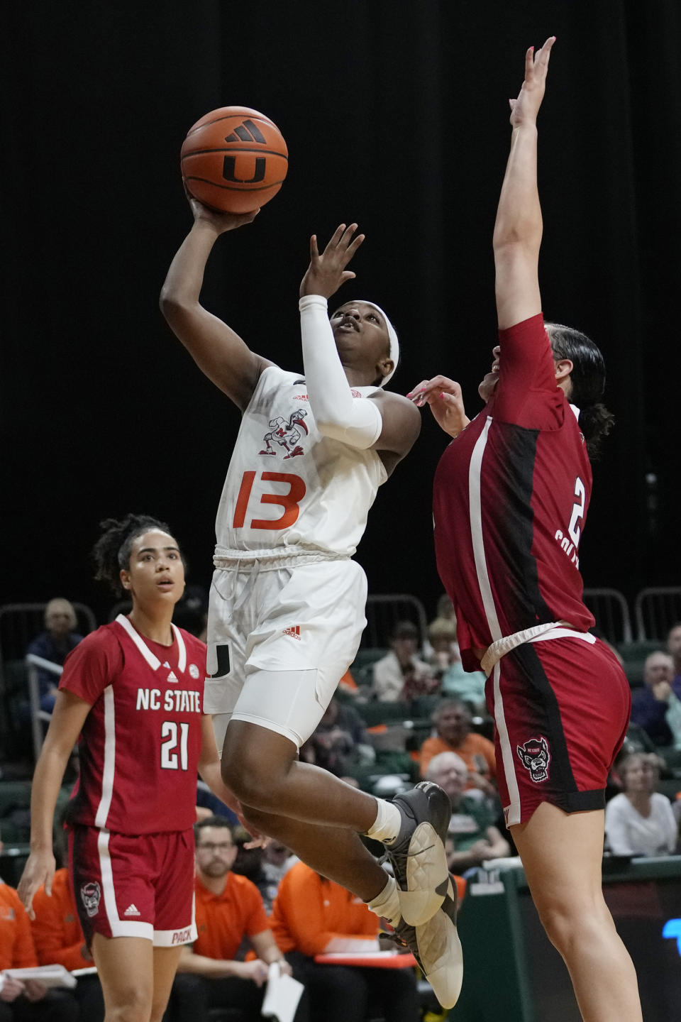 Miami guard Lashae Dwyer (13) shoots as North Carolina State forward Mimi Collins (2) defends during the second half of an NCAA college basketball game Thursday, Jan. 18, 2024, in Coral Gables, Fla. (AP Photo/Lynne Sladky)