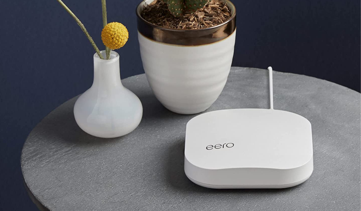 an eero router on a table with a potted plant and a bud vase