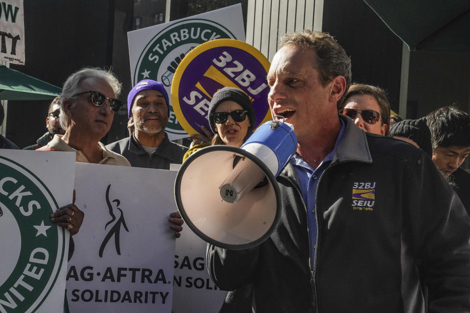 Manny Pastreich, right, president of service workers union SEIU local 32BJ, address a coalition of unions and supporters of Starbucks workers, during a rally outside a midtown Manhattan Starbucks coffee store, calling for "fair schedules and wages," Thursday, Nov. 16, 2023, in New York. Pastreich said, "if you don't know your schedule how do you take care of your families?" (AP Photo/Bebeto Matthews)