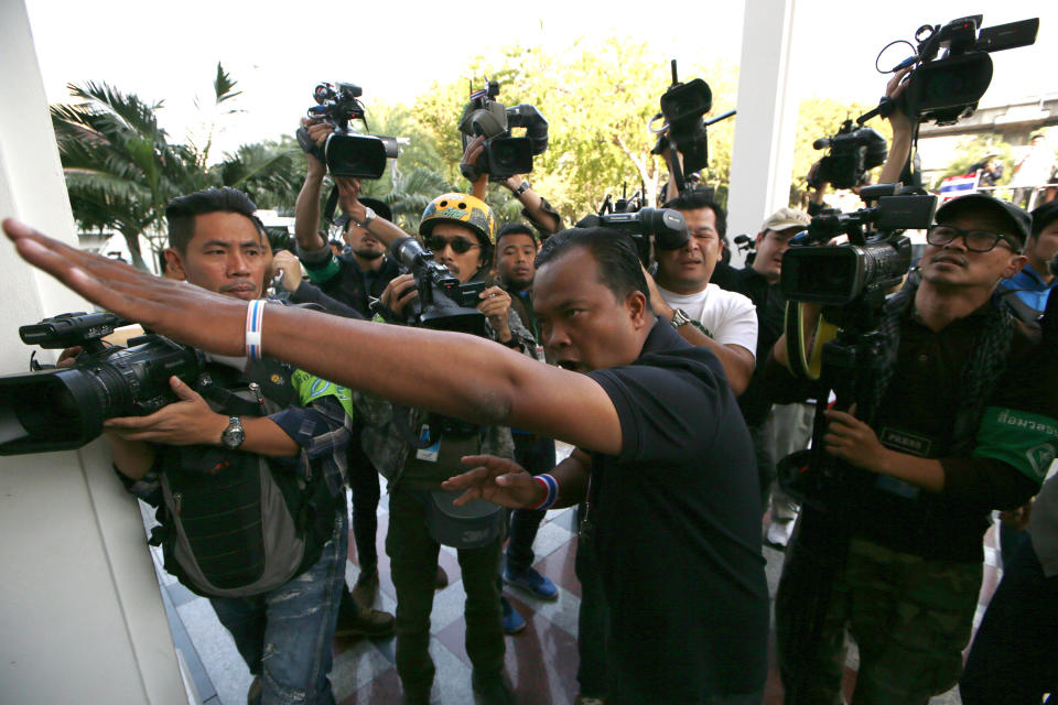 An anti-government protester, center, tells policemen guarding the building inside police headquarters to withdraw during a close down operation, Saturday, Jan. 18, 2014 in Bangkok, Thailand. A grenade thrown into a crowd of marching anti-government demonstrators in Thailand's capital killed one man and wounded dozens of people, an ominous development that raises tensions in the country's political crisis and the specter of more bloodshed to come. (AP photo/Wason Wanichakorn)