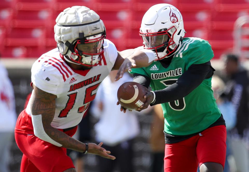 Malik Cunningham hands off to Jalen Mitchell during practice at Cardinal Stadium on Sunday, April 3, 2021