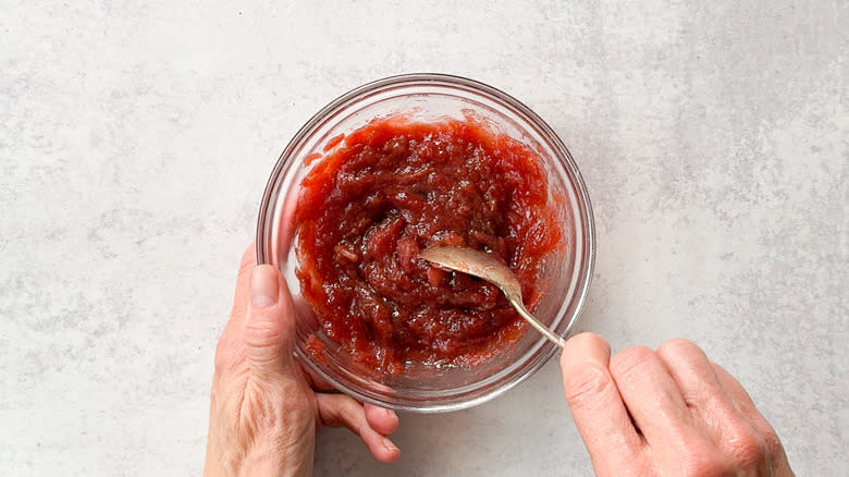 Stirring rhubarb compote in glass bowl with spoon