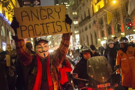 New York Police Department (NYPD) policemen use motorbikes to create a cordon as protesters, demonstrating decisions by grand juries in New York and Missouri not to indict white police officers in the killings of unarmed black men, hold placards while marching down Fifth Avenue in Manhattan, New York, December 23, 2014. REUTERS/Adrees Latif