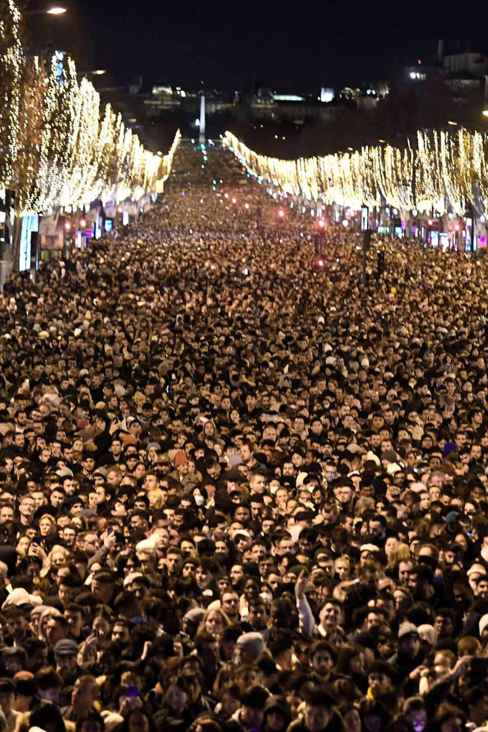 People gather on the Champs-Elysee as they wait for the New Year's Eve fireworks in Paris (AFP via Getty Images)