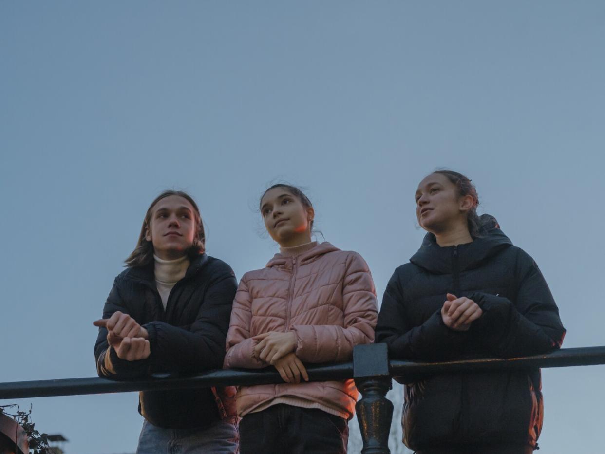 A boy, left, and two lean on a railing