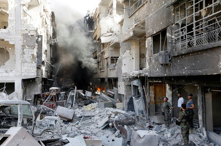 Syrian army soldiers stand among the rubble of damage buildings in al-Hajar al-Aswad, Syria May 21, 2018. REUTERS/Omar Sanadiki