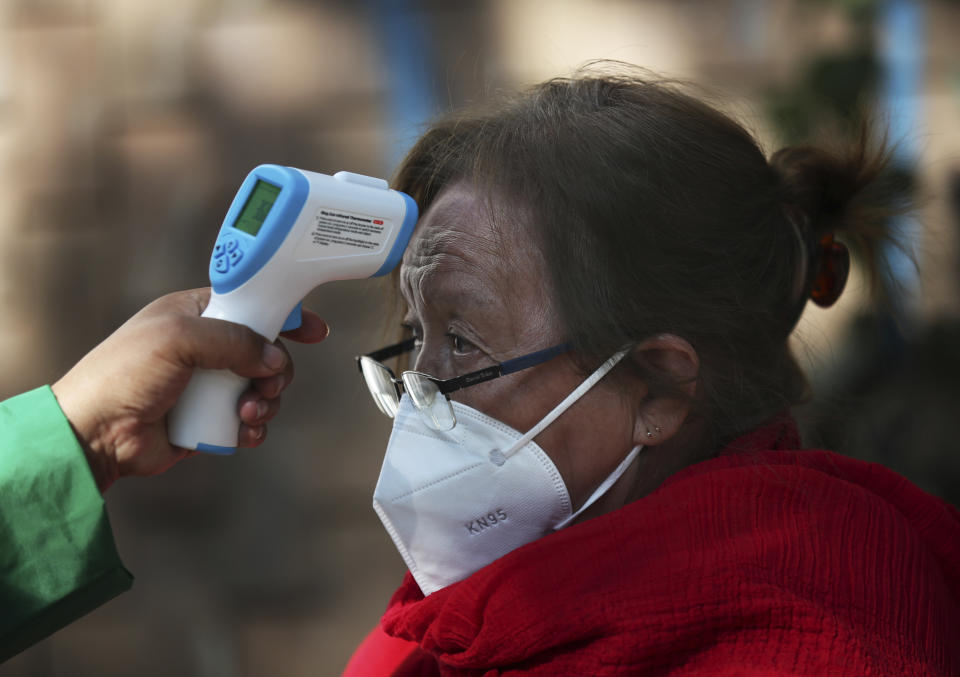 A woman gets her temperature taken as she waits to get the AstraZeneca vaccine against COVID-19 in the Magdalena Contreras area of Mexico City, Monday, Feb. 15, 2021, as Mexico begins to vaccinate people over age 60 against the new coronavirus. (AP Photo/Marco Ugarte)