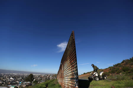 A member of the U.S. border patrol inspects the area where the border fence separating Mexico and the United States is interrupted, on the outskirts of Tijuana, Mexico. REUTERS/Edgard Garrido