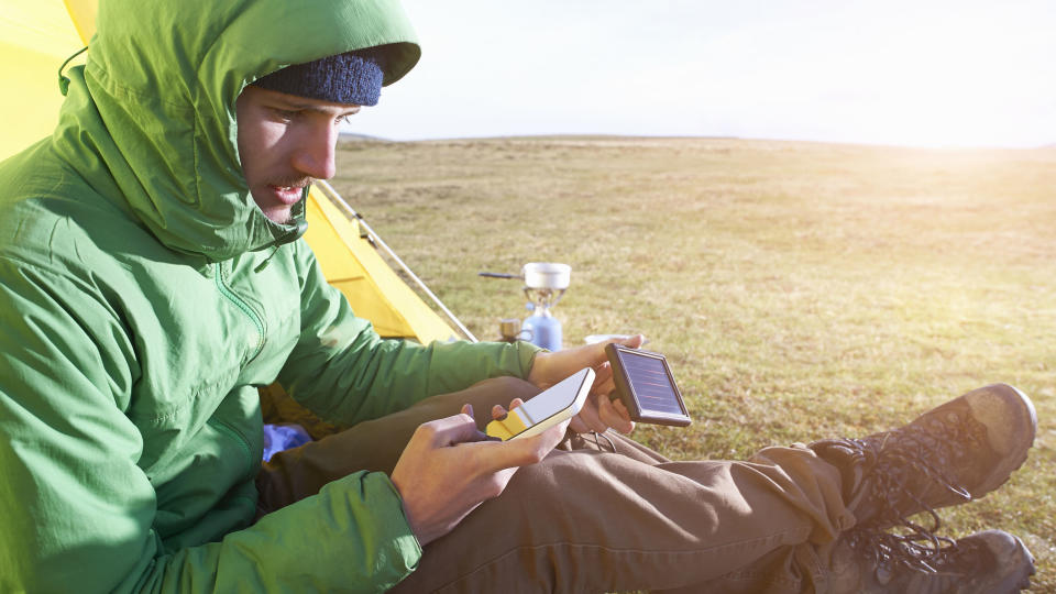 how to charge phones when camping: man charging phone using solar charger