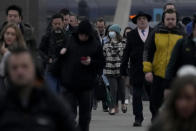 Workers walk over London Bridge towards the City of London financial district during the morning rush hour, in London, Monday, Jan. 24, 2022. The British government have asked people to return to working in offices starting Monday as they ease coronavirus restrictions. (AP Photo/Matt Dunham)