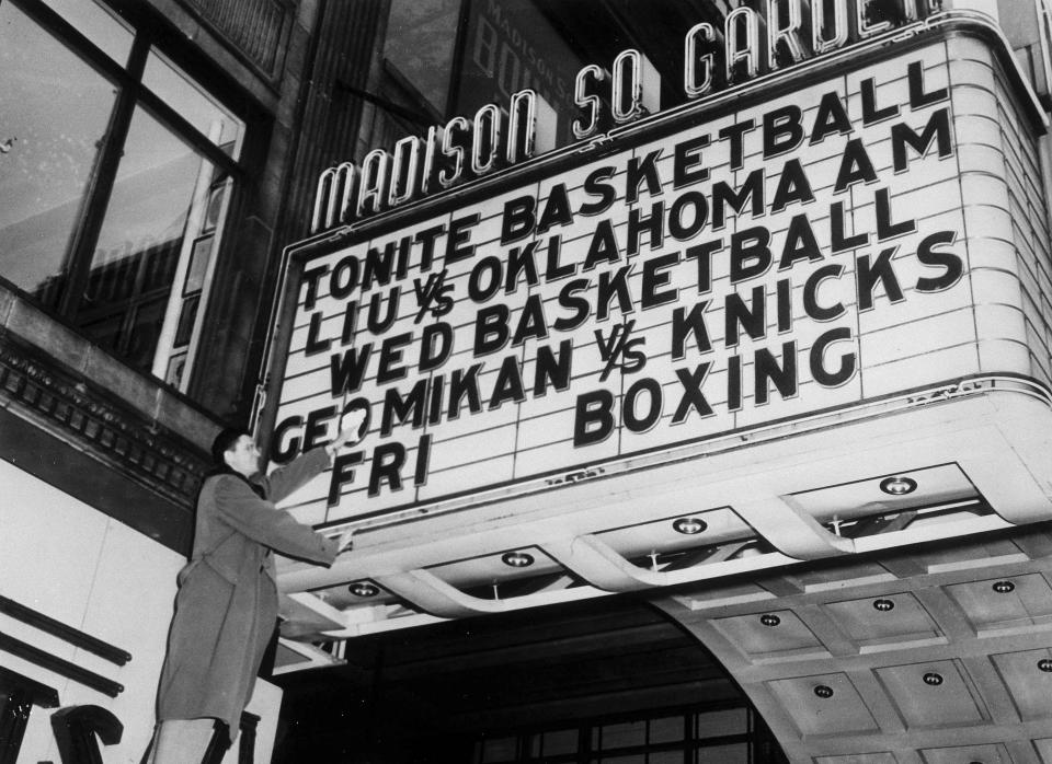 FILE - In this Dec. 13, 1949, file photo, George Mikan of the Minneapolis Lakers polishes off the sign on the marquee of Madison Square Garden in New York to make sure his name shines brightly for tomorrow's game. (AP Photo/Jacob Harris, File)