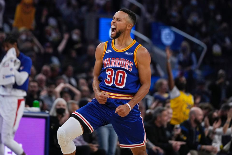 Stephen Curry flexes and screams while celebrating on the court.