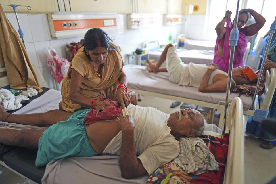 FILE - A woman wipes the body of her husband with cold cloth to keep him cool from heat at the government district hospital in Ballia, Uttar Pradesh state, India, Monday, June 19, 2023. As the heat breaks records, weakening and sickening people, it’s worth remembering that dire heat waves have inspired effective efforts to prevent heat illness. (AP Photo/Rajesh Kumar Singh, File)