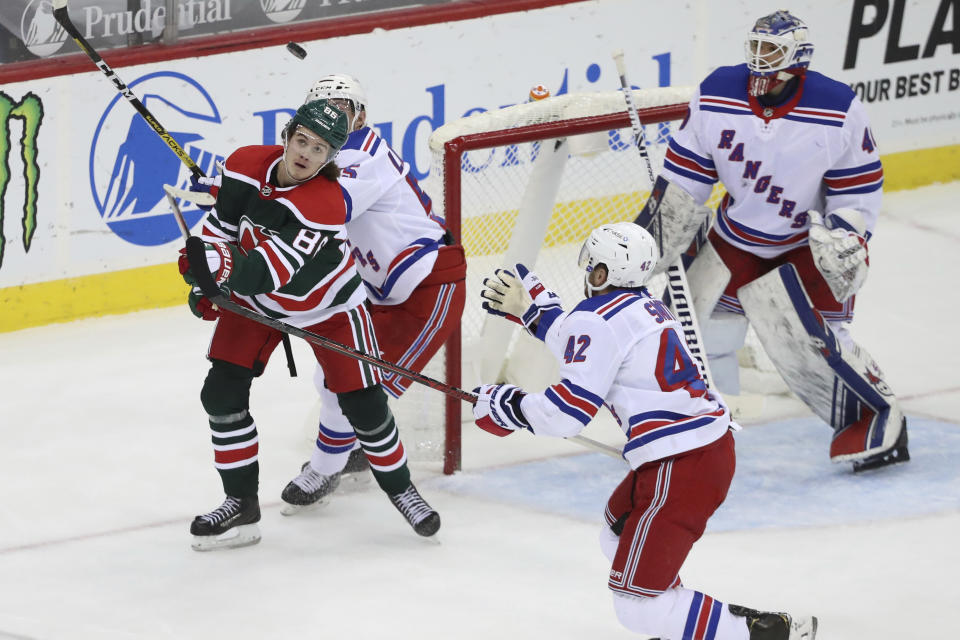 New Jersey Devils center Jack Hughes (86), New York Rangers defensemen Ryan Lindgren (55) and Brendan Smith (42) compete for the puck in front of Rangers goaltender Alexandar Georgiev (40) during the third period of an NHL hockey game in Newark N.J., on Saturday, March 6, 2021. (Andrew Mills/NJ Advance Media via AP)