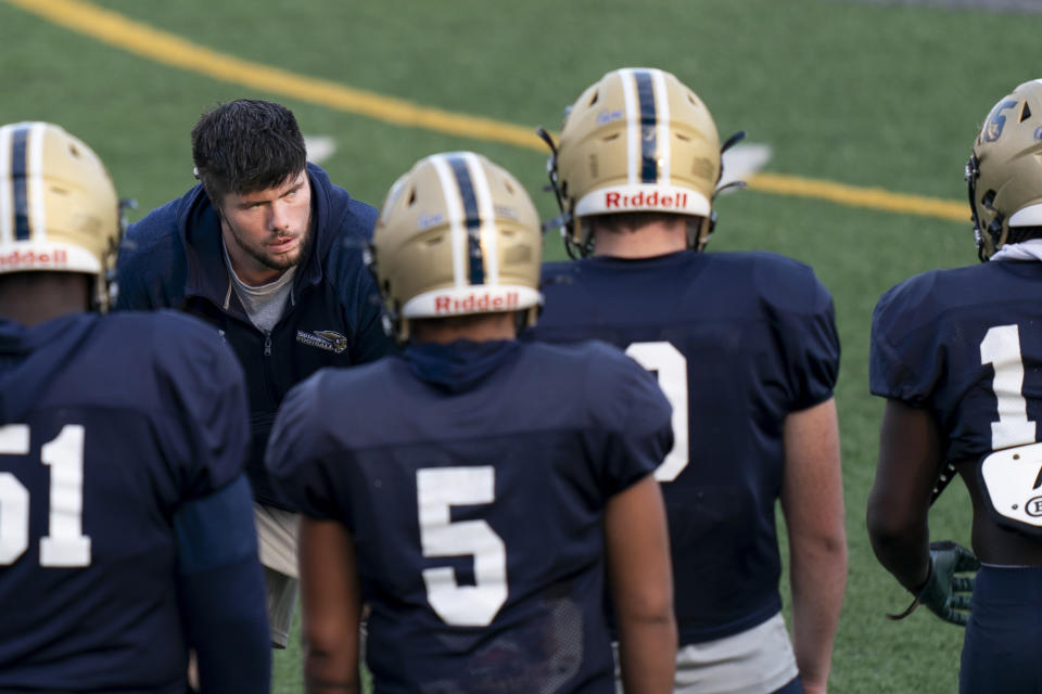 Gallaudet assistant coach Shelby Bean, left, coaches players during football practice at Hotchkiss Field, Tuesday, Oct. 10, 2023, in Washington. As a Deaf football player for four years at Gallaudet, Bean called defensive plays with American Sign Language and dealt with other obstacles hearing opponents would never need to worry about. Now he was on the sideline earlier this month when a new football helmet the school developed with AT&T allowed the plays to be displayed visually inside quarterback Brandon Washington's helmet. (AP Photo/Stephanie Scarbrough)