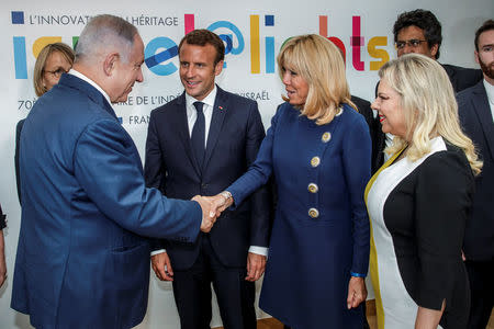 French President Emmanuel Macron stands by his wife Brigitte Macron (2ndR) who shakes hands with Israeli Prime Minister Benjamin Netanyahu and his wife Sara Netanyahu during the opening ceremony of the France-Israel season event in Paris, France, June 5, 2018. Christophe Petit Tesson/Pool via Reuters