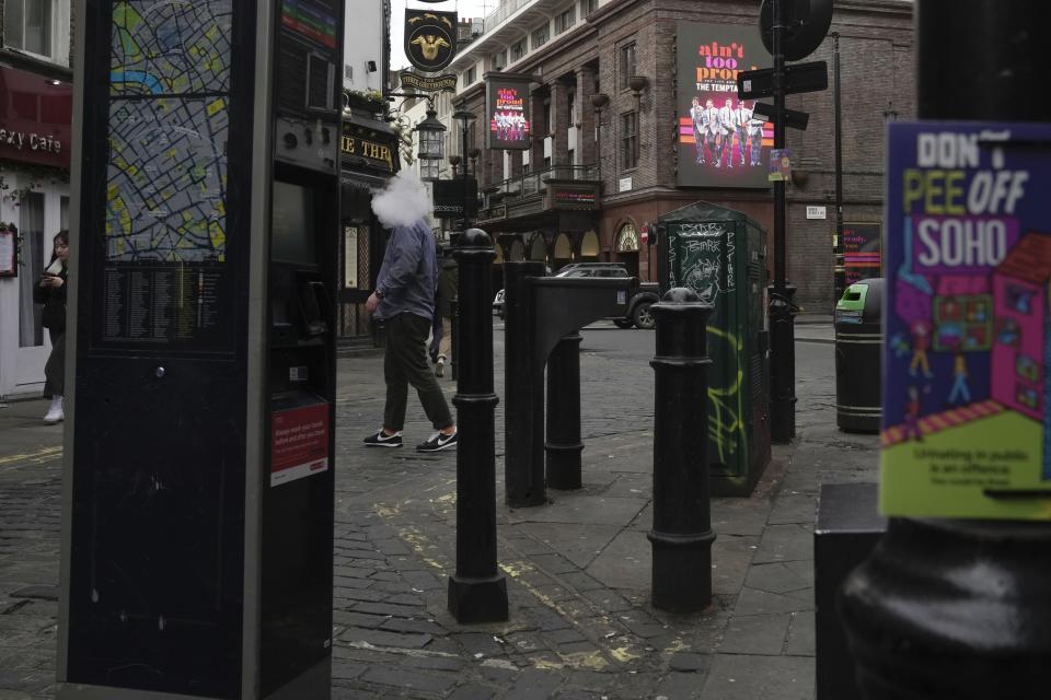 A man smokes on a street in central London, Thursday, Feb. 2, 2023. The Bank of England is expected to raise interest rates by as much as half a percentage point Thursday as it seeks to tame the double-digit inflation fueling a cost-of-living crisis, public-sector strikes and fears of recession. (AP Photo/Kin Cheung)